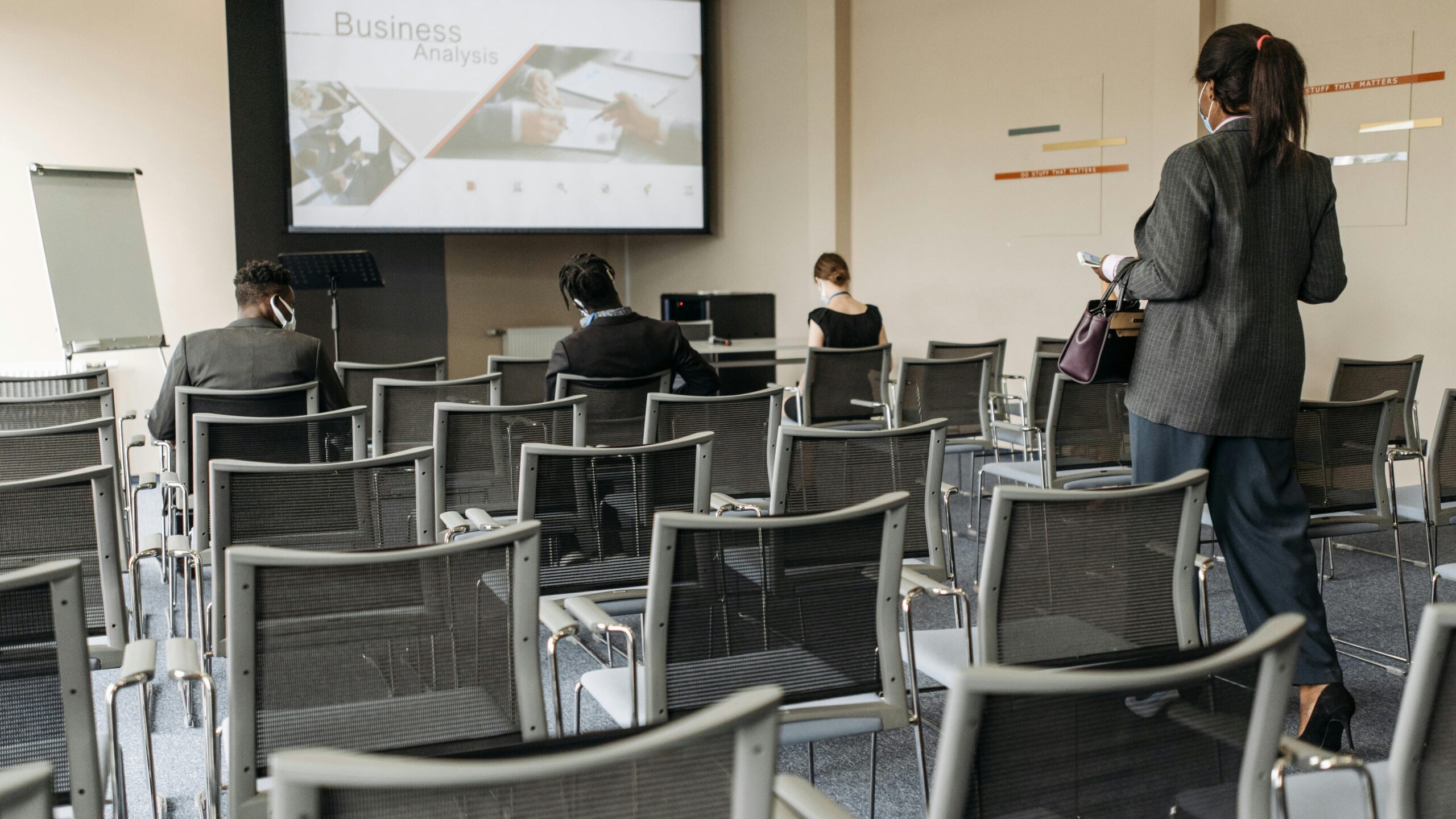 Conference room setup for a business seminar, with attendees wearing masks.